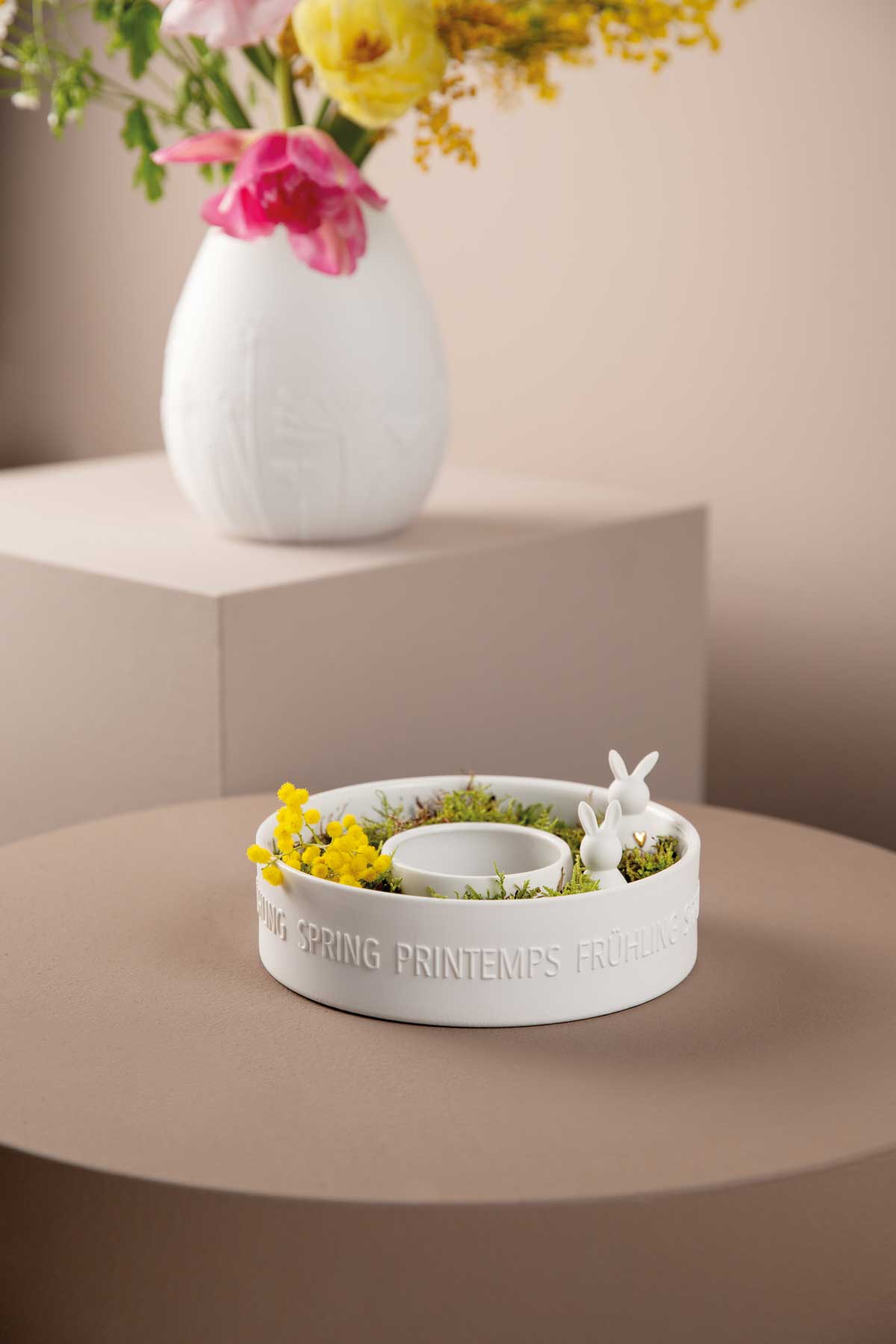 weiße Vase und Schale aus Porzellan mit Blumen und kleinen weißen Porzellanosterhasen in Schale