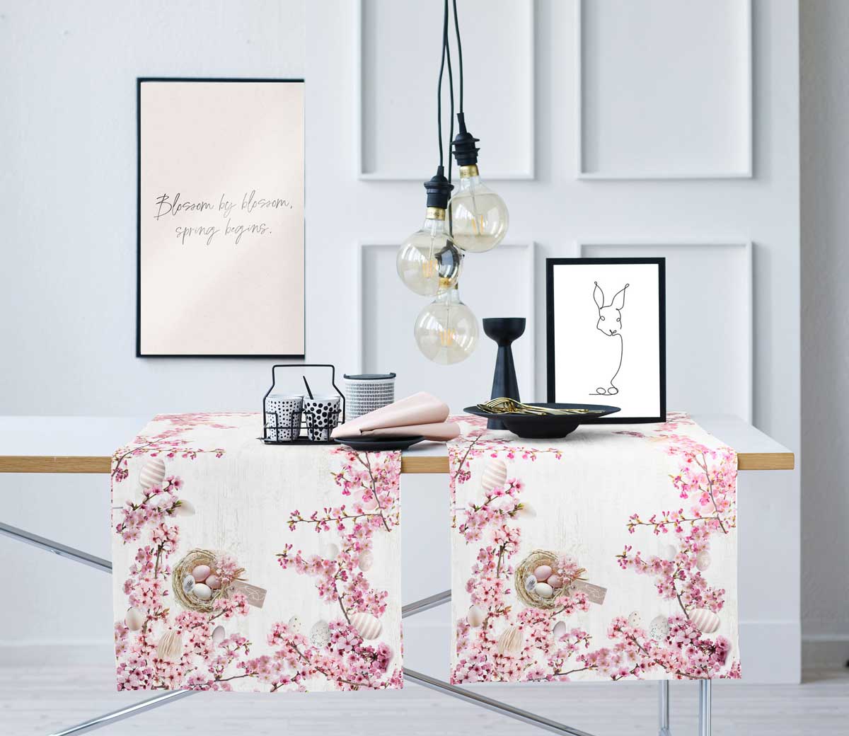 Tischläufer mit weiß-rosa Osterblütendekor auf Tisch unter kleinen Accessoires