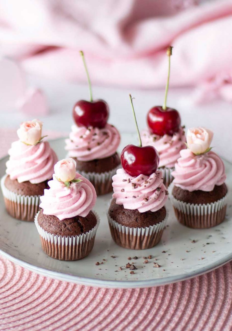 ein Teller mit Muffins garniert mit Sahne und Kirschen 