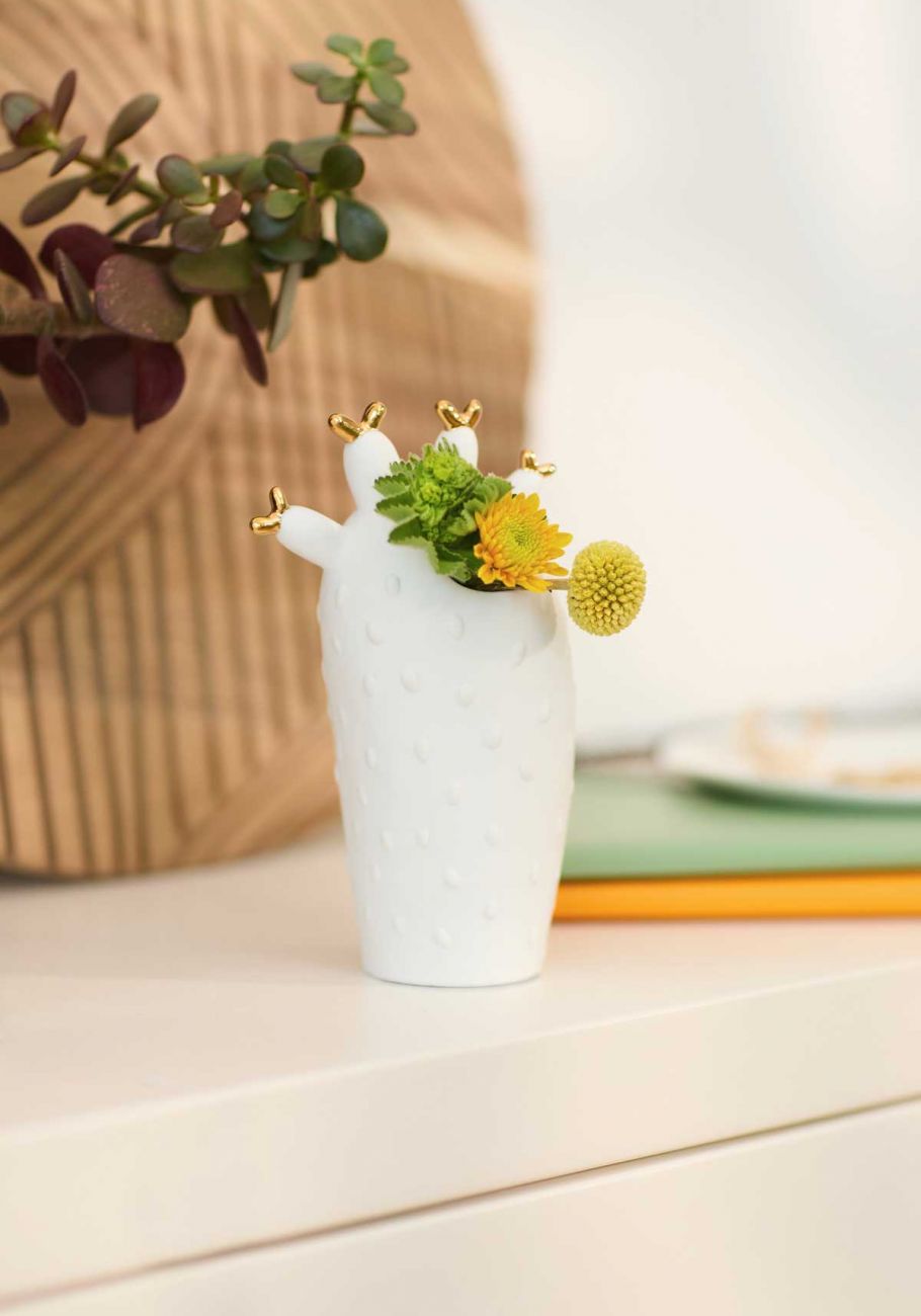 weisse Vase in Kaktusform mit goldfarbenen Dornen gefüllt mit kleinen Blüten